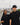 Two people wearing black clothing with a logo, standing in front of Toronto cityscape.